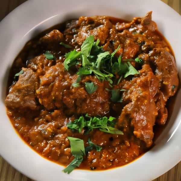 A close-up of a rich, dark Indian curry with tender meat pieces, garnished with fresh cilantro.